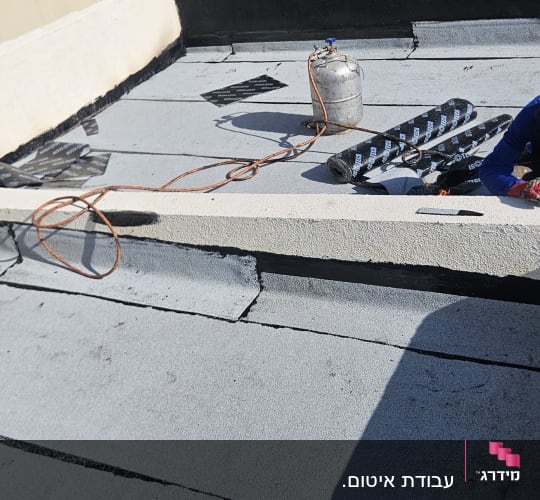 עבודת איטום על גג עם יריעות וחומרי איטום